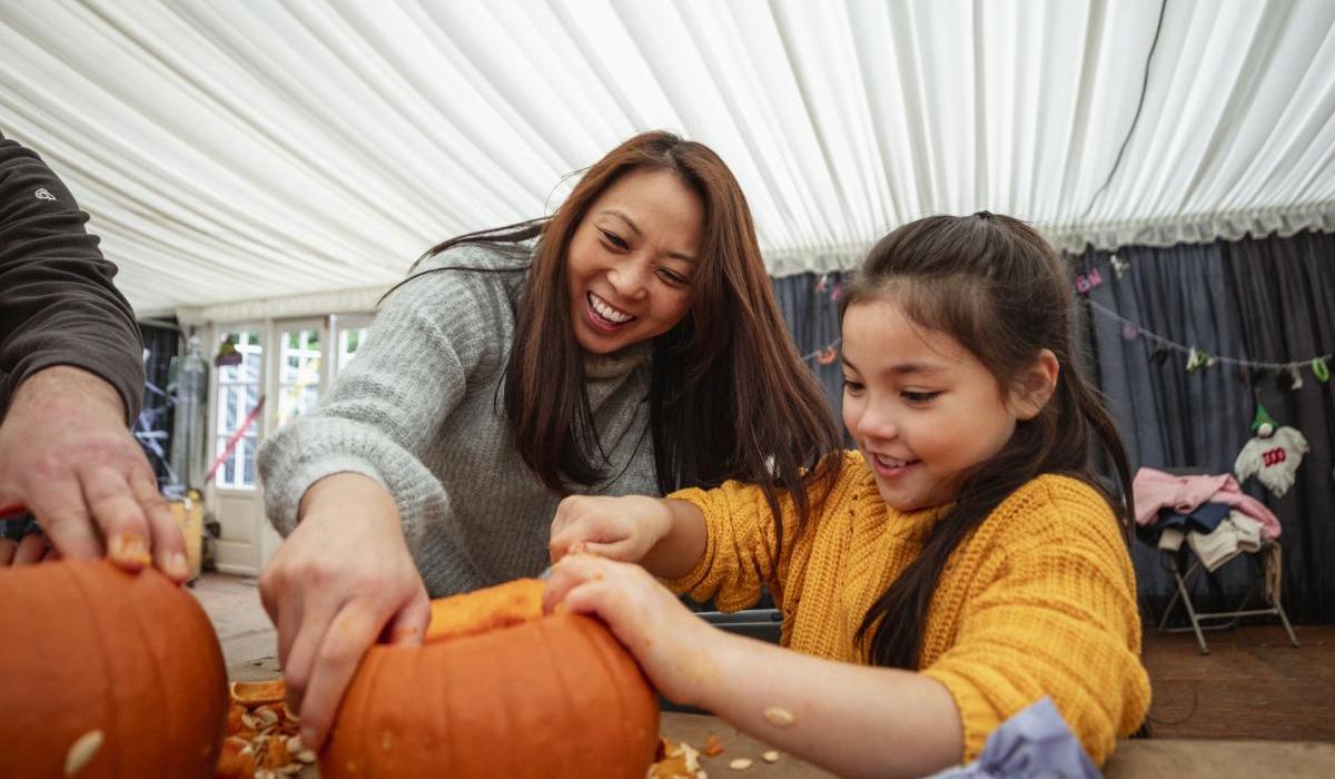Mother and daughter carving pumpkins at a farm after picking them in preparation for Halloween.