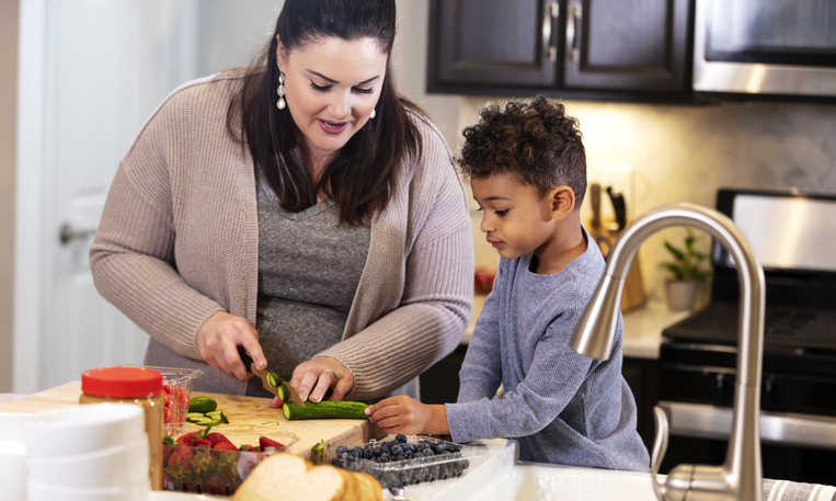 Little boy helping mother make lunch in kitchen