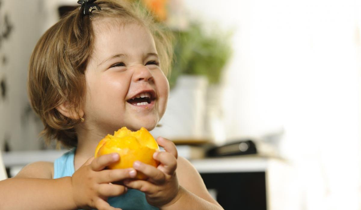 Girl eating a peach.