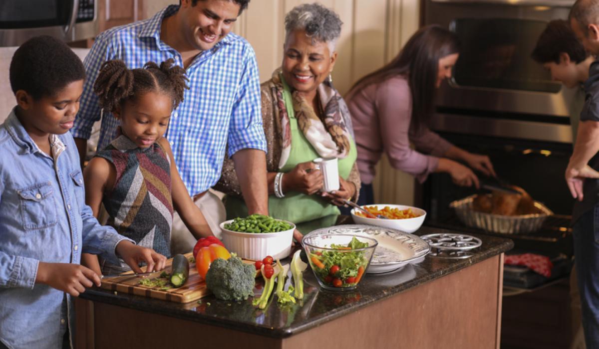 Diverse family in home kitchen cooking Thanksgiving dinner.