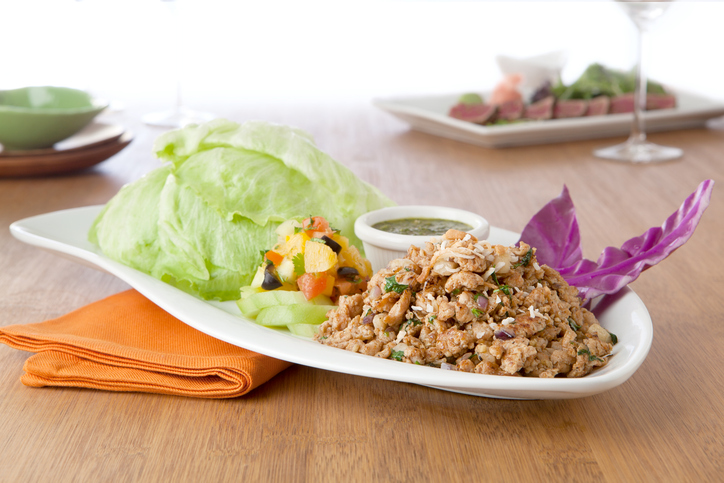 a plate filled with lettuce wrap ingredients, chicken, lettuce, chutney