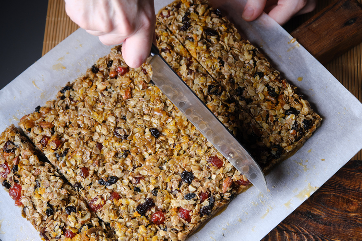 Woman is cutting and wrapping homemade granola bars