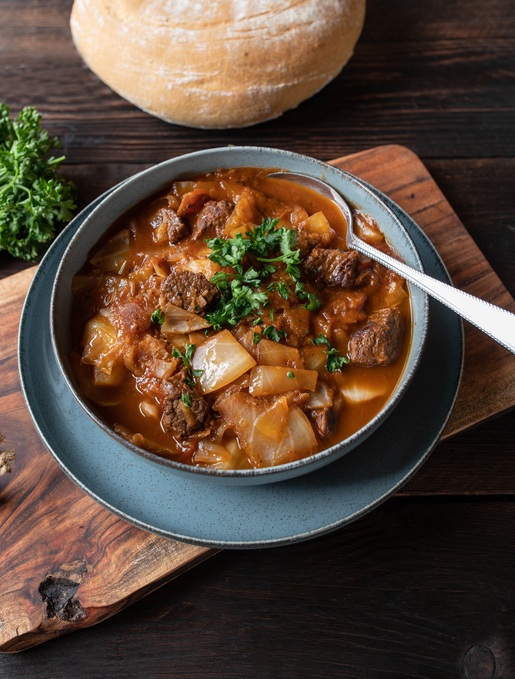 Delicious homemade romanian beef stew with cabbage and vegetables. Served with bread isolated on rustic and wooden table background. Top view
