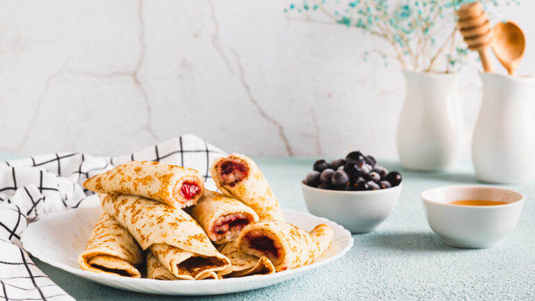Homemade pancake rolls with berry filling on a plate on the table web banner