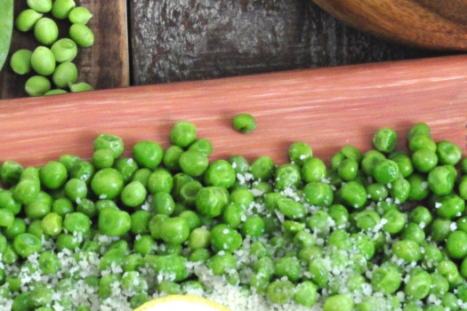 peas in a bowl with parmesan cheese and a lemon wedge