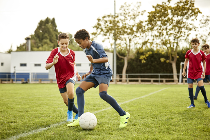 Teenagers practicing soccer in sports field