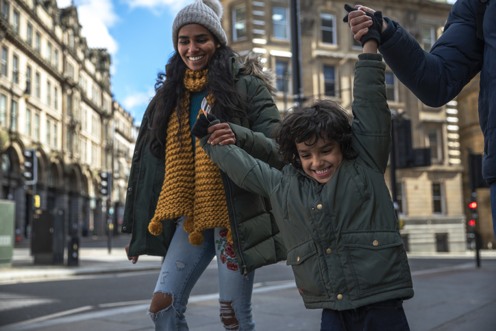 A family of three, walking through the city. 