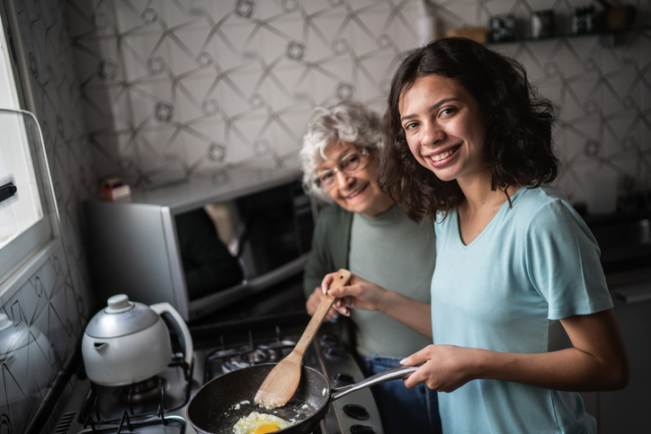 Portrait of granddaughter and grandmother cooking together at home