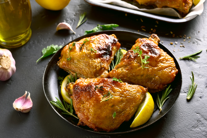 Tasty grilled chicken thighs on plate over black stone table