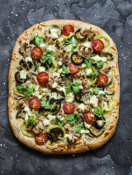 Roasted vegetables vegetarian flatbread on a dark background, top view. Cauliflower, eggplant, tomato, zucchini vegetarian pizza