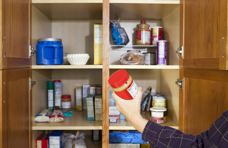 A person reaching inside their kitchen cupboard.