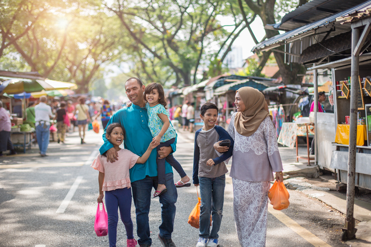 Malaysian family of five walking through market street in city of Kuala Lumpur