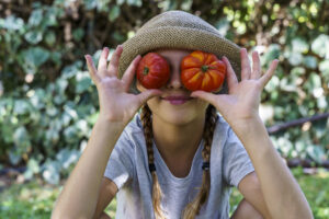 Cute little girl holding a bunch of fresh organic tomatoes in her eyes.