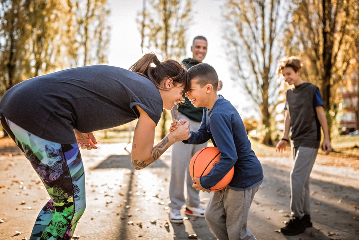 Parent and child playing basketball with friends on a fall day.