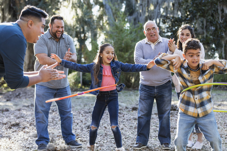 Multigenerational family hula hooping outside together.