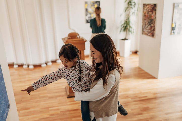 Parent and child looking at art while walking through a museum.