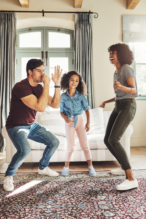 Full length shot of a happy young family of three dancing together at home
