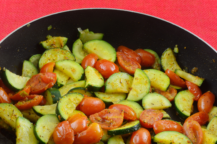 Sliced zucchini squash and grape tomato vegetable side dish sauteed in frying pan