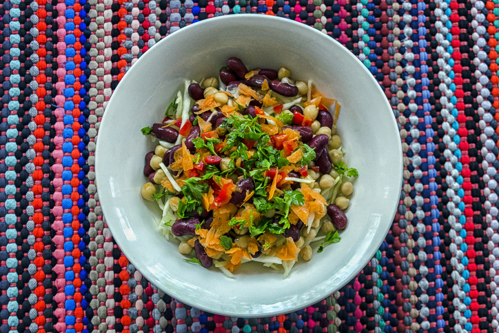 An overhead shot of bean, carrot, parsley, red bell pepper, cabbage, and chickpea salad bowl