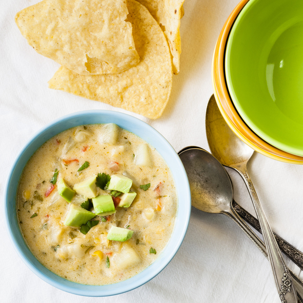 Overhead Cheesy Chili Corn Chowder with corn chips and bowls and spoons