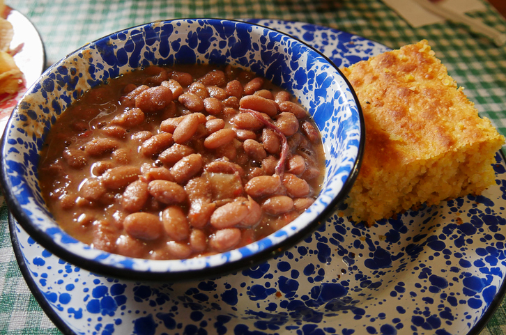 Serving of home-cooked beans and corn bread served in blue patterned tin plates