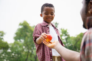 Son gives red apple to his father