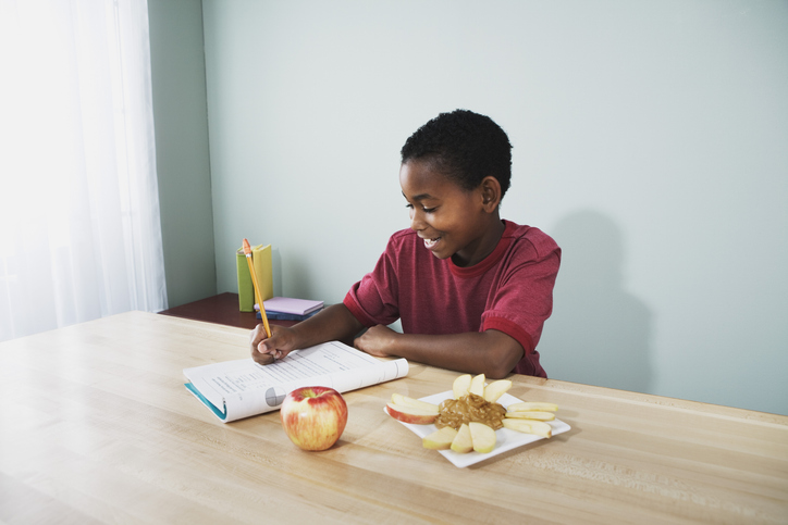 Boy doing homework and having a snack