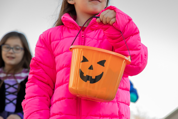 Group of children dressed in costumes trick-or-treating on Halloween in suburban neighborhood