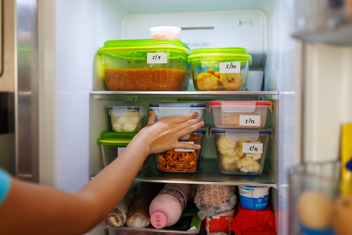 Food leftovers packaged in boxes inside a home fridge with dates written on.