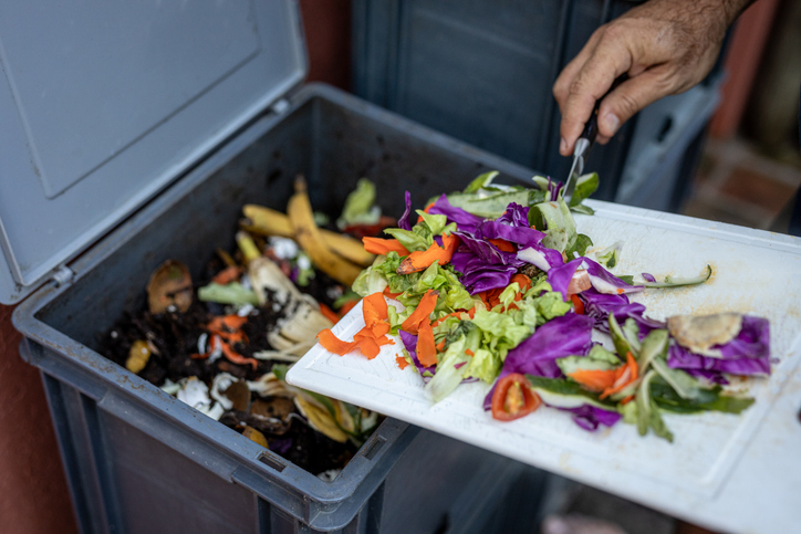 Man composting organic remains in home composter