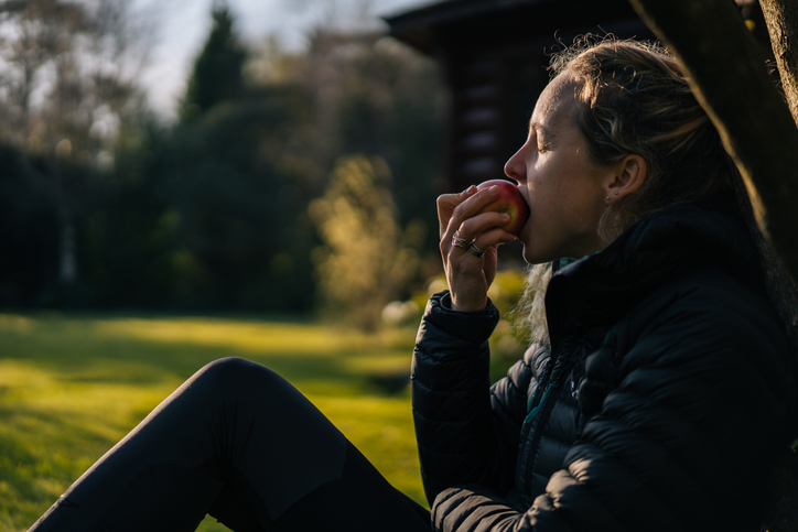 Young woman relaxes in garden while eating apple