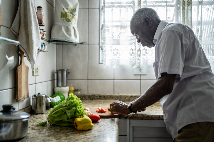 Senior man cutting tomatoes in the kitchen at home