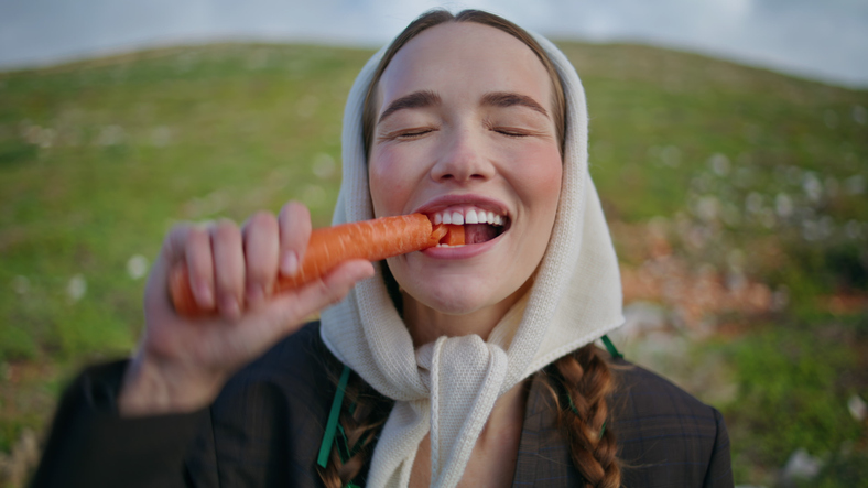 Woman biting fresh carrot healthy vegetable closeup. 