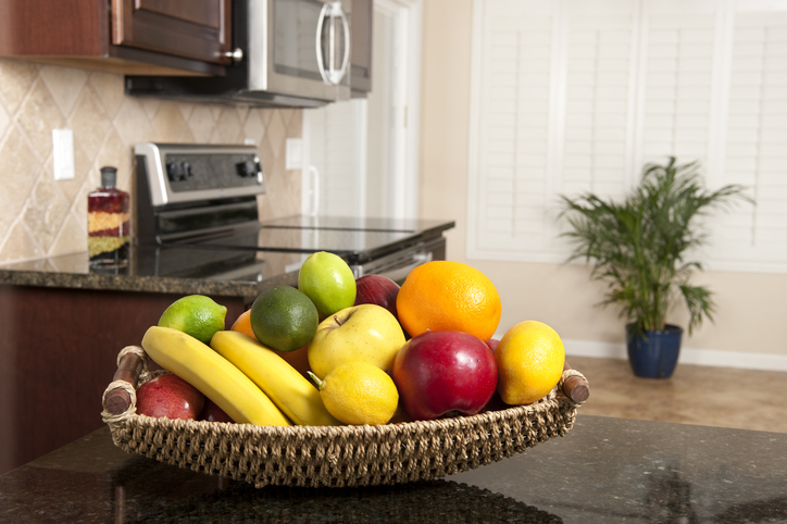 A fresh fruit basket on a granite countertop in a newly remodeled kitchen.