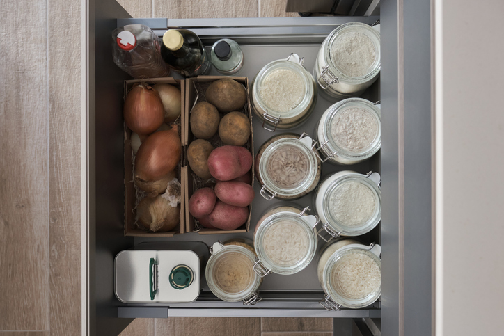 Variety of flours, rices, potatoes, onion, garlic, olive oil, vinegar in kitchen drawer. Zero waste storage concept.