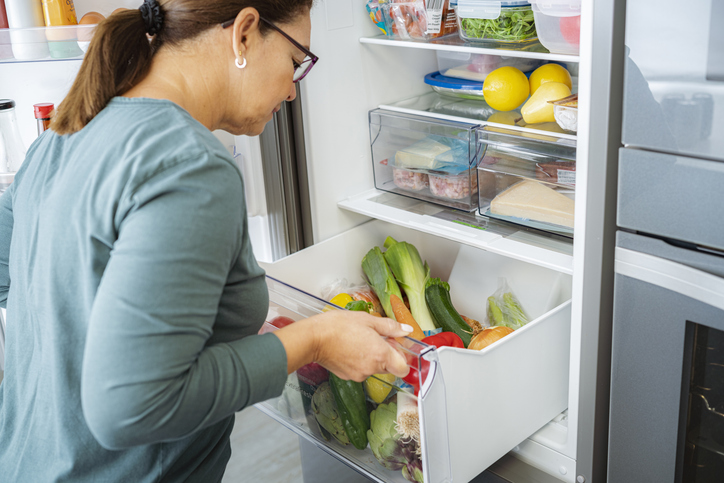 Woman opening refrigerator vegetables drawer