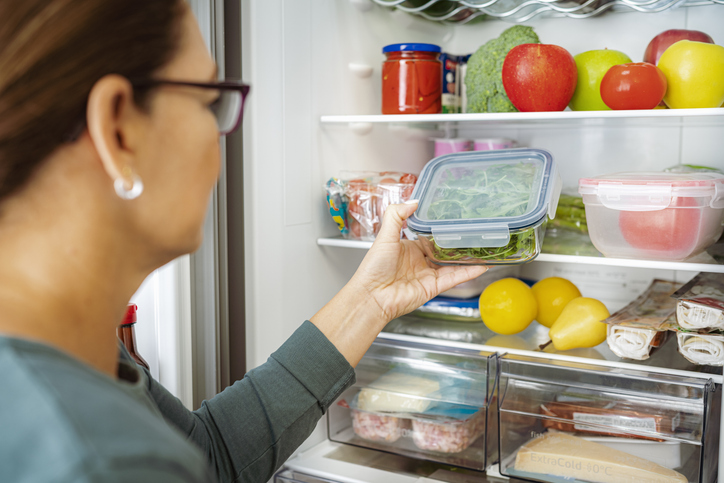 Close up of woman taking container with food from fridge