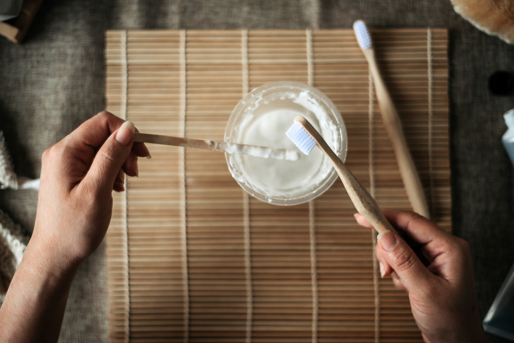 direct above of young women hands holding wooden brush and tools with handmade toothpaste