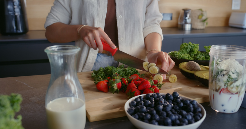 Hands, woman and cutting fruit for smoothie with organic ingredients, preparation and weight loss. Person, process and healthy drink with nutrition benefits, meal replacement and wellness at house