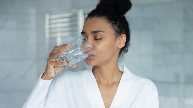 woman holding glass drinking still water in the morning