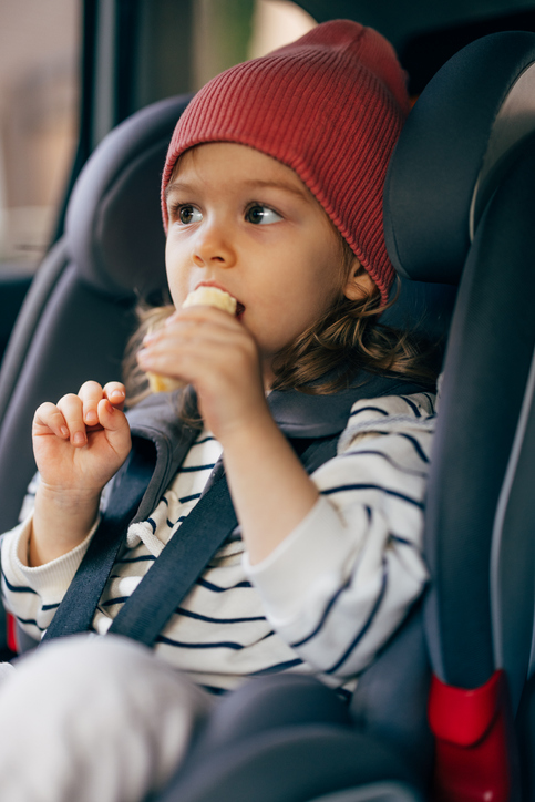 Portrait of a Cute Little Girl Eating Lunch While Traveling by Car