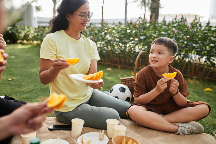 Boy Eating Orange at Picnic