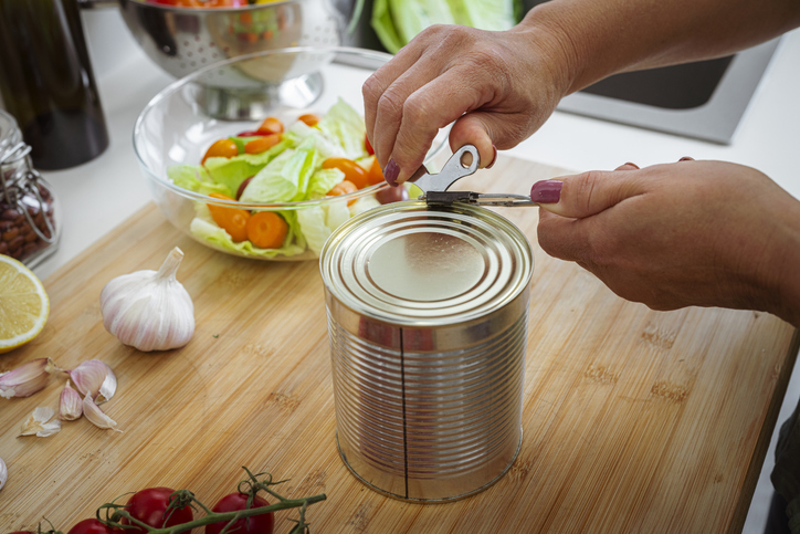 Woman opening lid of  canned food on kitchen counter. Cooking or preparing recipe at home, vegetarian food
