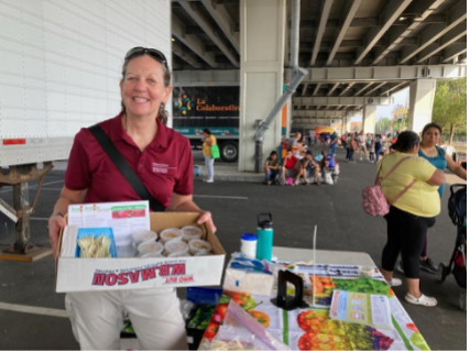 Female member of Umass Amherst Nutrition group holding a box at a table